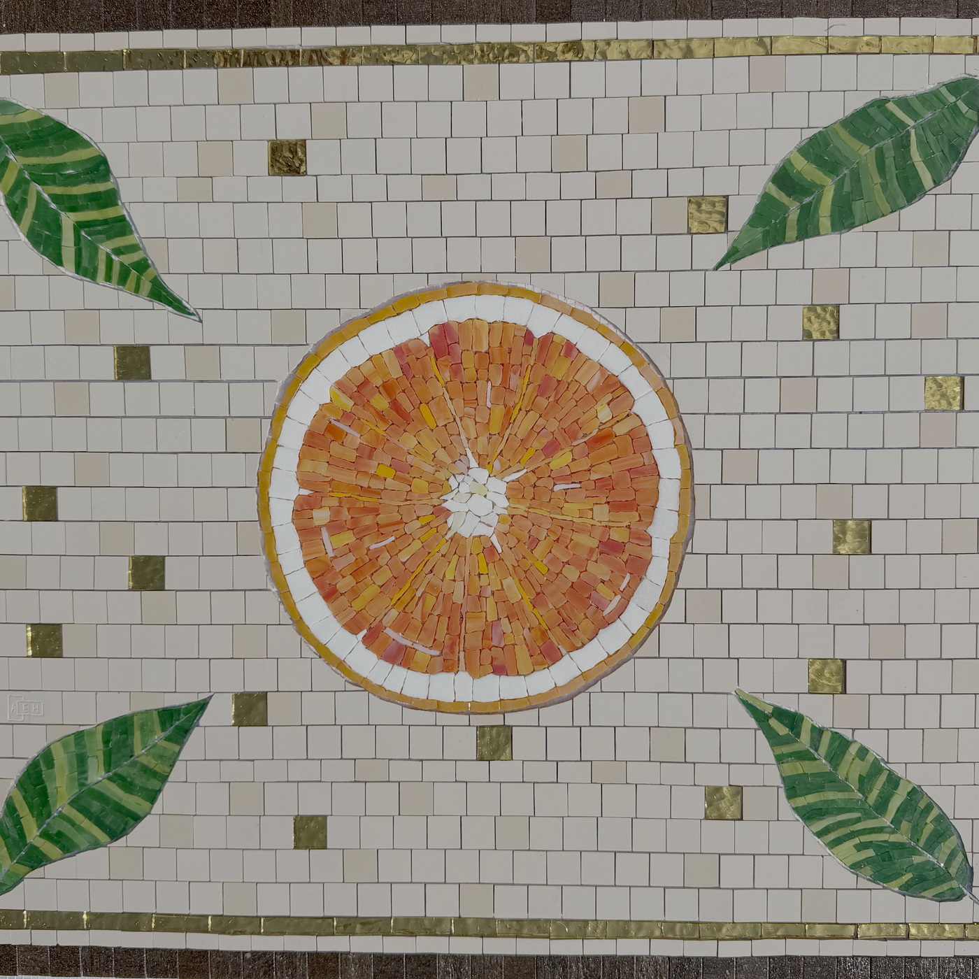 Pièce en mosaïque avec motif d'orange, feuilles vertes et tesselles dorées