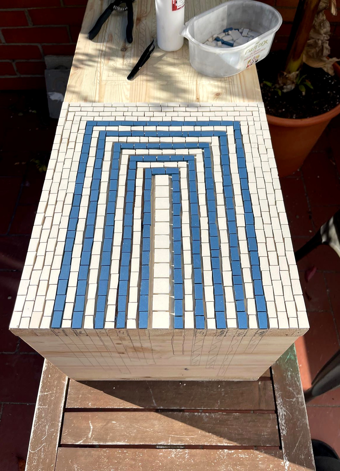 Pose des tesselles bleues et blanches sur une table basse